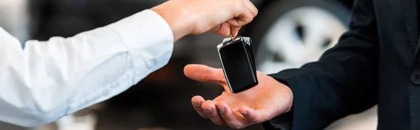 Panoramic shot of car dealer giving car key to man — Stock Photo