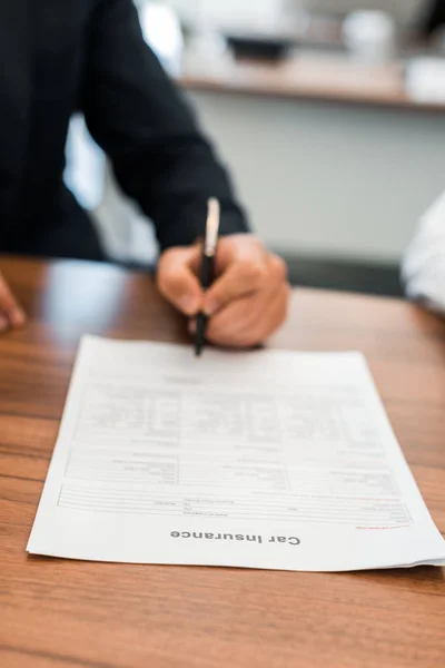 Enfoque selectivo del hombre firma contrato de seguro de coche - foto de stock