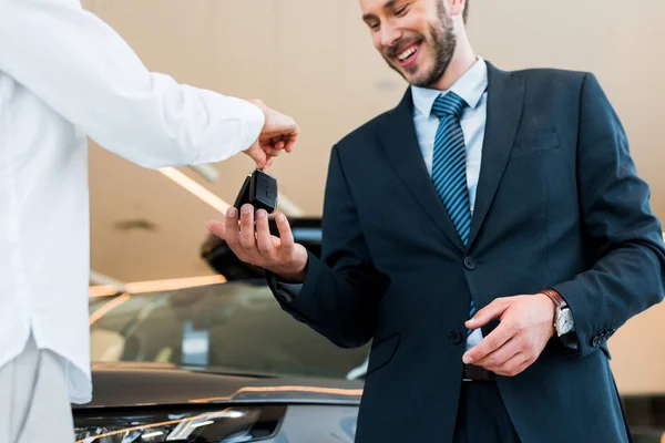 Selektiver Fokus der Frau gibt Autoschlüssel an glücklichen bärtigen Mann — Stockfoto