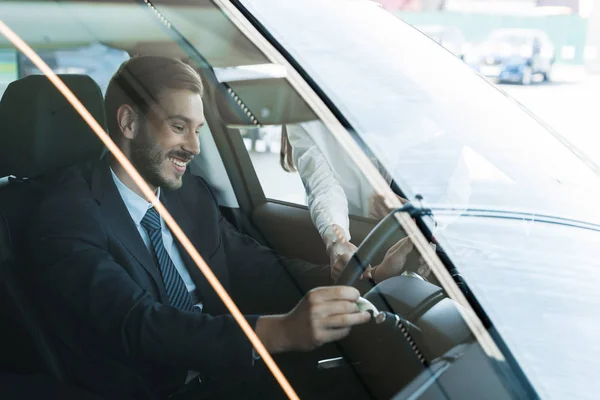 Обрізаний вид жінки, що стоїть біля щасливого чоловіка в машині — стокове фото