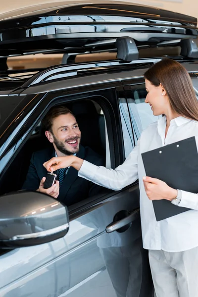 Selective focus of beautiful woman giving car key to man in car — Stock Photo