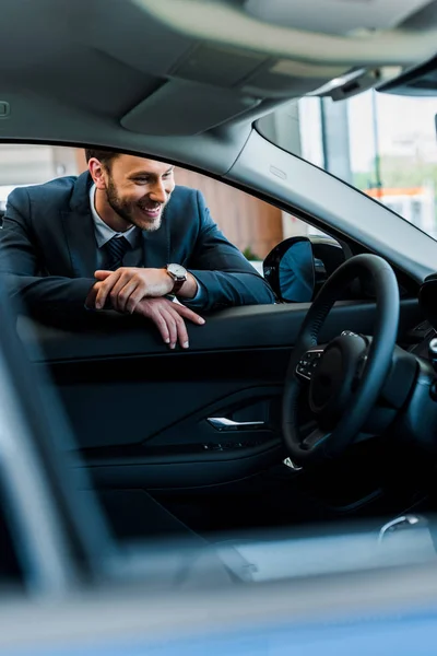 Selective focus of happy bearded man looking at modern car — Stock Photo