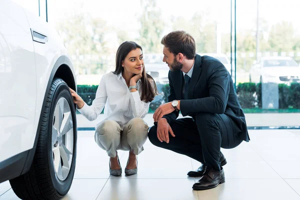 Cheerful woman sitting near car and looking at bearded man — Stock Photo