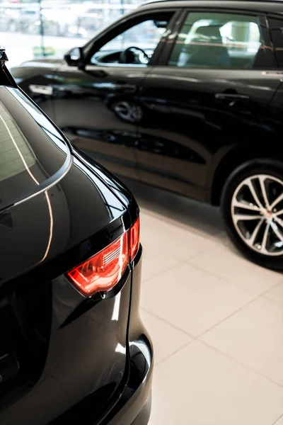 Foco selectivo de los coches brillantes negros en sala de exposición de coches - foto de stock