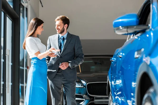 Happy woman gesturing while standing and looking at handsome bearded man — Stock Photo