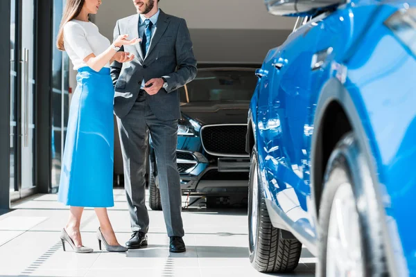 Обрізаний вид жінки жестикулює, стоячи біля бородатого чоловіка і автомобілів — стокове фото
