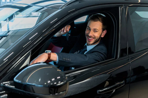 Вибірковий фокус щасливого бородатого чоловіка, який тримає ключ від машини, сидячи в машині — стокове фото
