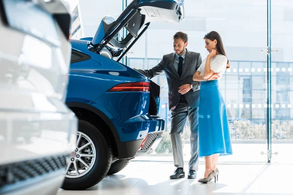 Enfoque selectivo de hombre barbudo y mujer hermosa mirando el maletero del coche - foto de stock