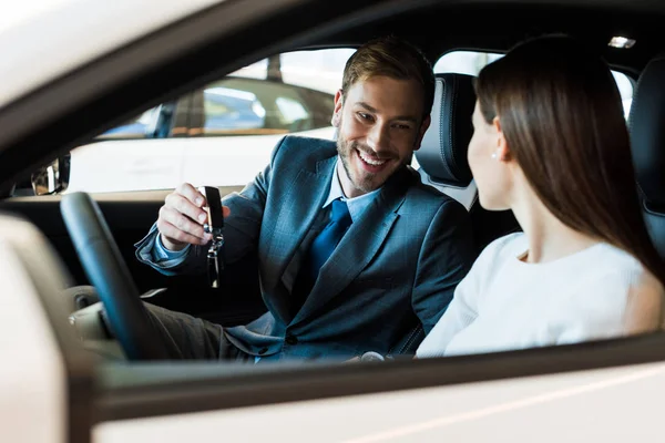 Enfoque selectivo de hombre barbudo feliz sosteniendo la llave del coche cerca de la mujer - foto de stock