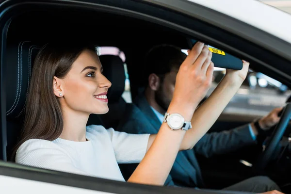Избирательный фокус улыбающейся женщины, сидящей в машине с мужчиной — стоковое фото