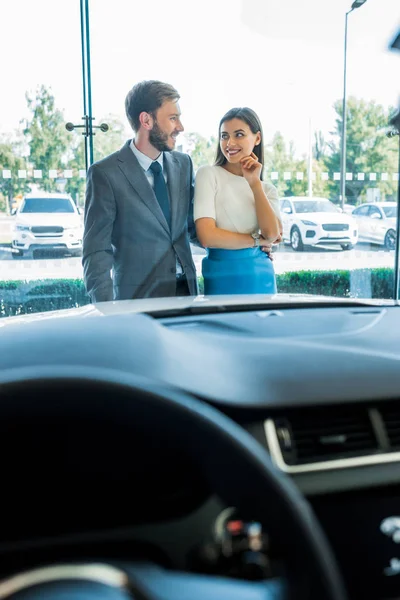 Selective focus of bearded man and attractive woman looking at each other near car — Stock Photo