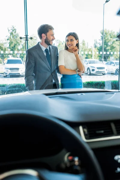 Messa a fuoco selettiva di uomo barbuto e donna attraente guardando l'un l'altro vicino auto — Foto stock