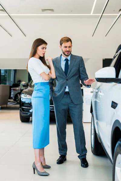 Mujer sorprendida mirando el coche y de pie con el hombre - foto de stock