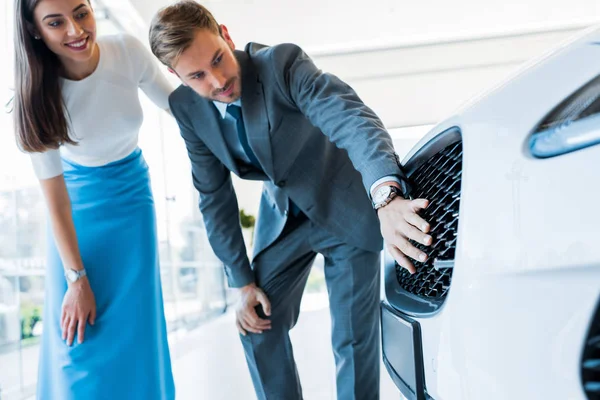 Hombre guapo tocando coche cerca de mujer atractiva — Stock Photo