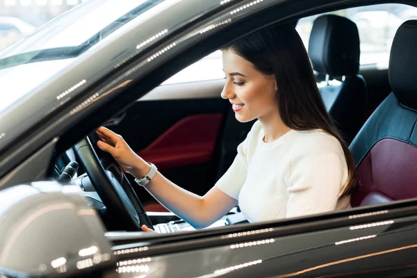 Selektive Fokussierung der positiven Frau, die im Auto das Lenkrad berührt — Stockfoto