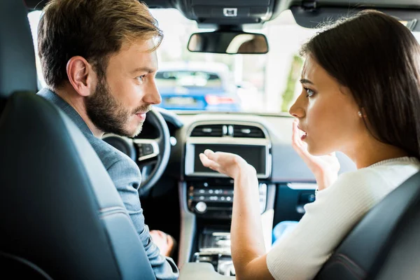Selective focus of man and woman looking at each other in car — Stock Photo