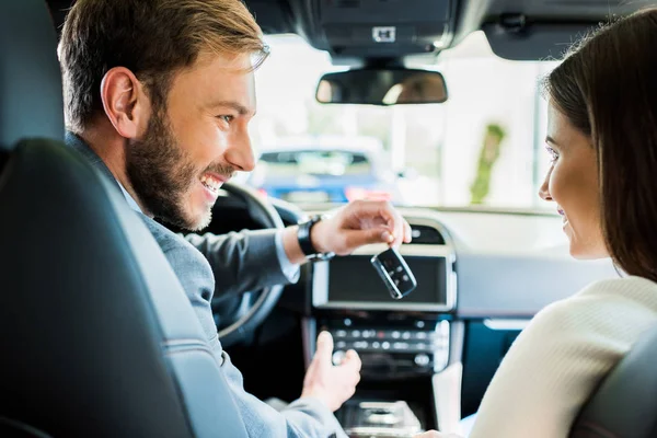 Foco seletivo de homem feliz e mulher olhando um para o outro no carro — Fotografia de Stock