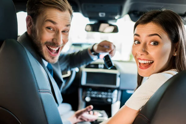 Foco seletivo de homem feliz e mulher olhando para a câmera no carro — Fotografia de Stock