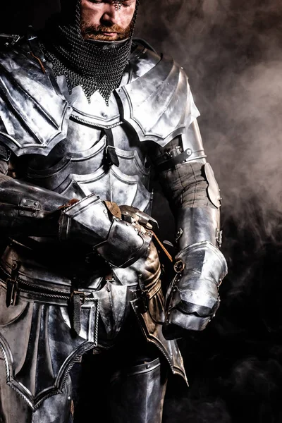 Vue recadrée du chevalier en armure sur fond noir — Photo de stock