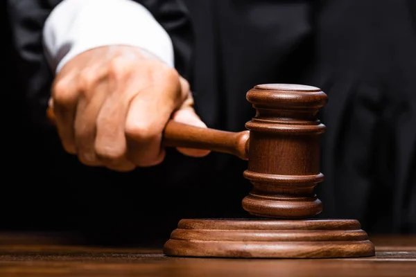 Corte vista do juiz em roupão judicial sentado à mesa e batendo com martelo — Fotografia de Stock