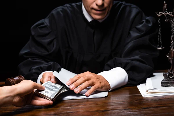 Cropped view of woman giving bribe to judge isolated on black — Stock Photo