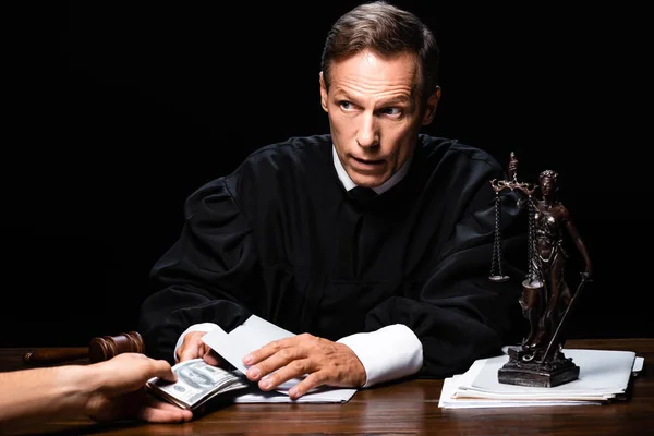 Cropped view of woman giving bribe to judge isolated on black — Stock Photo