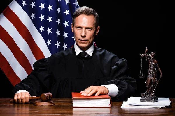 Судья в судейском халате держит молоток и кладет руку на книгу — стоковое фото