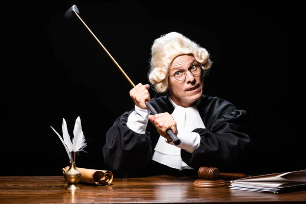 Angry judge in judicial robe and wig holding golf club isolated on black — Stock Photo