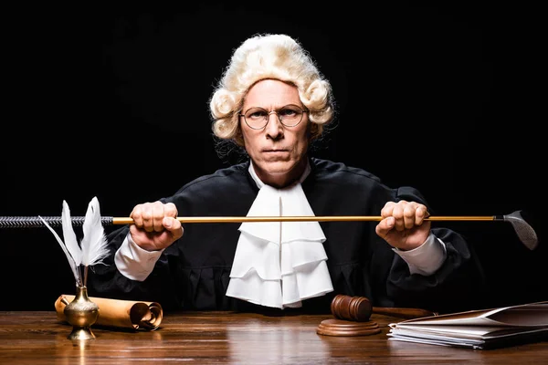 Angry judge in judicial robe and wig holding golf club isolated on black — Stock Photo