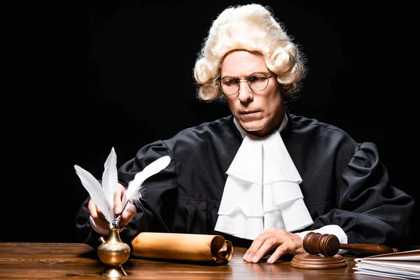 Judge in judicial robe and wig taking feather isolated on black — Stock Photo