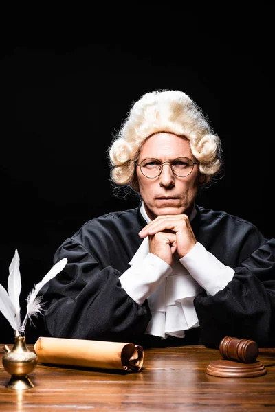 Серйозний суддя в судовому халаті і перука, дивлячись на камеру ізольовано на чорному — стокове фото