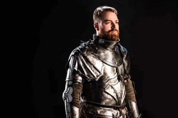 Handsome knight in armor looking away isolated on black — Stock Photo