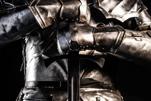 Vista recortada de caballero en la armadura que sostiene la espada aislado en negro - foto de stock