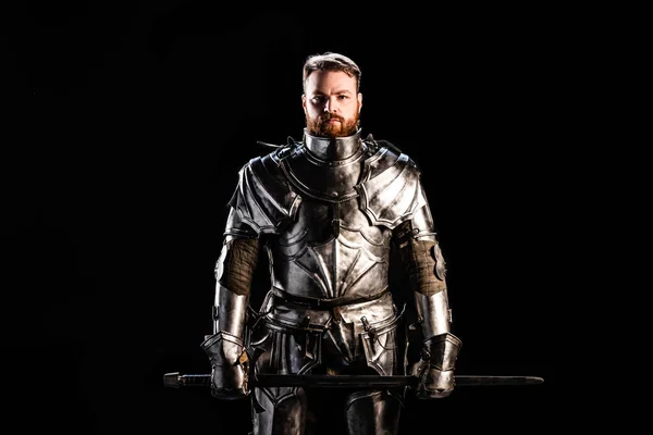 Bonito cavaleiro em armadura segurando espada isolado no preto — Fotografia de Stock