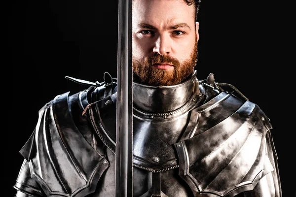 Schöner Ritter in Rüstung mit Schwert isoliert auf schwarz — Stockfoto