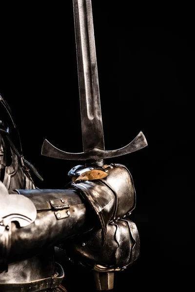 Vista ritagliata del cavaliere in armatura con spada isolata sul nero — Foto stock