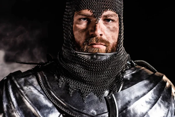 Schöner Ritter in Rüstung blickt in die Kamera auf schwarzem Hintergrund — Stockfoto