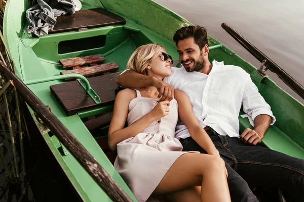 Веселая молодая пара смотрит друг на друга, сидя в лодке — стоковое фото