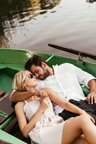 Happy young couple embracing while relaxing in boat on lake — Stock Photo
