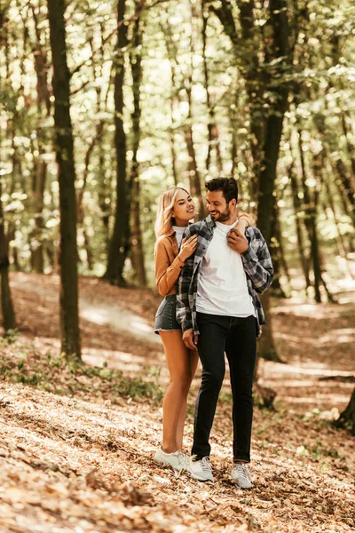 Happy girl embracing handsome boyfriend while walking in park — Stock Photo