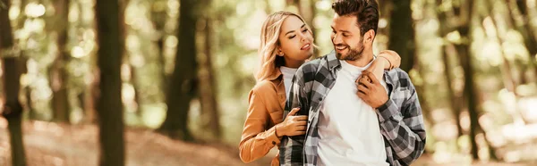 Panoramic shot of happy girl embracing handsome boyfriend while walking in park — Stock Photo