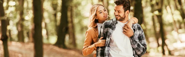 Panoramaaufnahme eines glücklichen Mädchens, das seinen hübschen Freund beim Spazierengehen im Park umarmt — Stockfoto