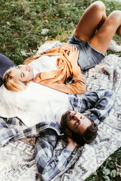 Vue aérienne du jeune couple heureux couché sur la couverture dans le parc — Photo de stock