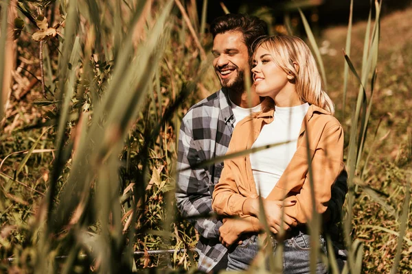 Foco seletivo de jovem feliz abraçando namorada sorridente na moita de sedge — Fotografia de Stock