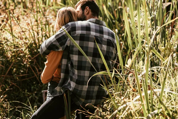 Vue arrière de l'homme en chemise à carreaux embrassant petite amie dans un fourré de carex — Photo de stock
