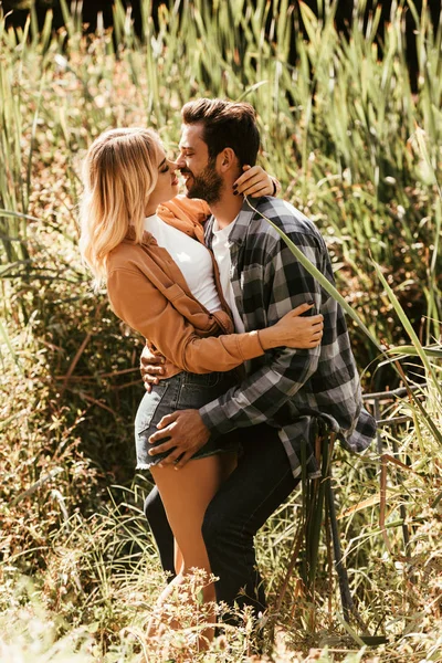 Felice giovane coppia abbracciare e baciare in boscaglia di carice nel parco — Foto stock