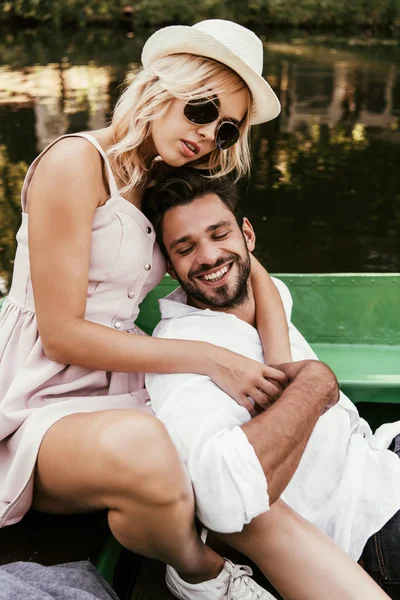 Красивая молодая женщина обнимает счастливого парня, сидя в лодке — стоковое фото
