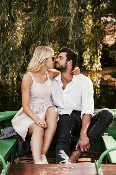 Feliz jovem casal beijando enquanto sentado no barco no lago — Fotografia de Stock