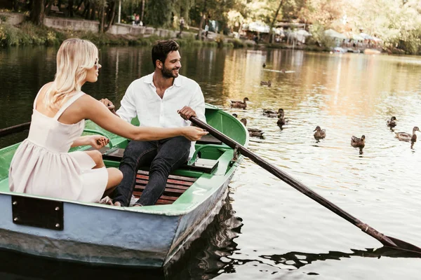 Feliz joven pareja en barco en el lago cerca de flack de patos - foto de stock