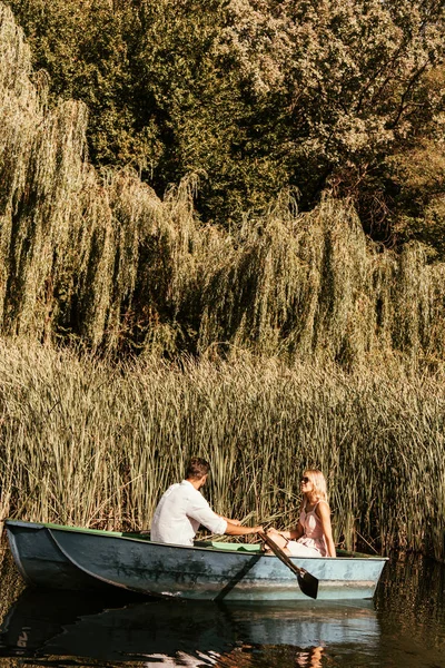 Jeune couple en bateau sur le lac près de fourrés de carex — Photo de stock